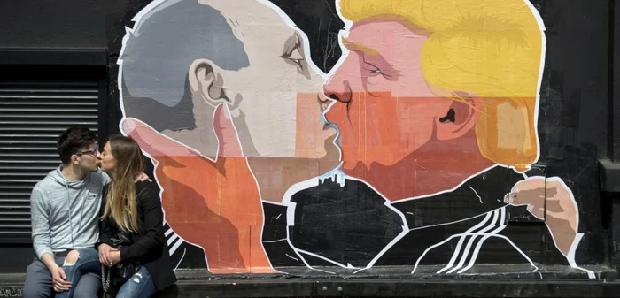 Un cuplu de îndrăgostiţi se sărută în faţa unui perete pe care sunt pictaţi preşedintele Rusiei Vladimir Putin care îl sărută pe candidatul republican la preşedenţia Statelor Unite Donald Trump. FOTO AP