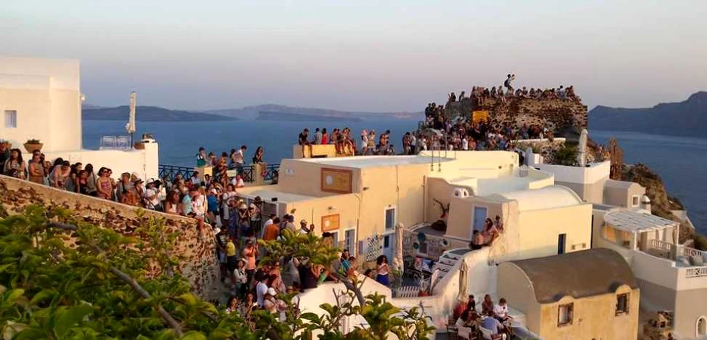 Turiştii aplaudă apusul în Oia, insula Santorini