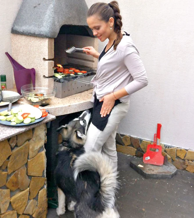 
    În timp ce învârtea  legumele pe grătar,  Cristina îşi alinta căţelul (fotografii: arhiva personală)  
