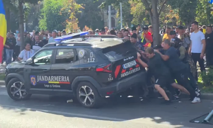 protestatarii din Piata Victoriei incercand sa rastoarne o masina a jandarmeriei png