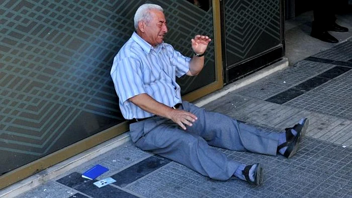 Fotografia cu pensionarul doborât de criza din Grecia şi plângând în faţa unei bănci a făcut înconjurul lumii FOTO AFP