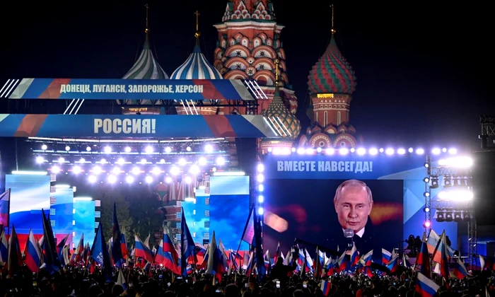 Vladimir Putin apare pe un ecran, în Piața Roșie din Moscova, adresându-se miilor de spectatori