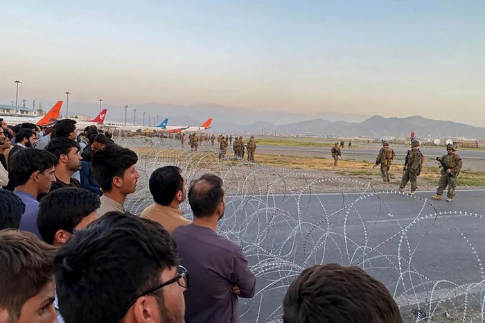 multimea de oamnei de pe aeroportul din kabul afganistan pazit de soladati americani foto Shakib Rahmani / AFP