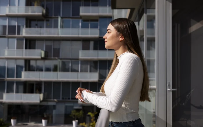 O tânără stă pe balconul apartamentului său