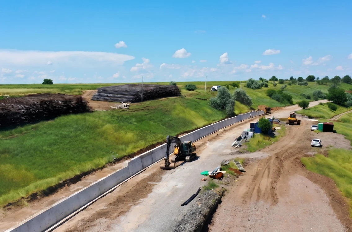 Șantier feroviar în zonă rurală, cu excavator și utilaje de construcții care lucrează la terasamente