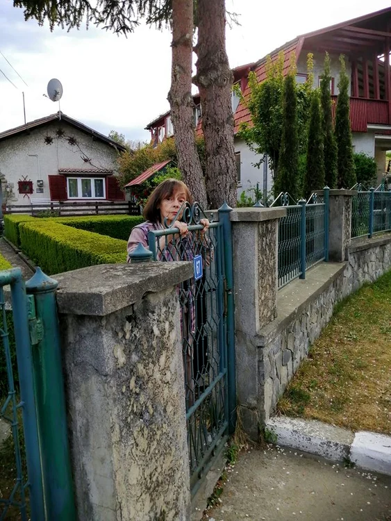 Marina Voica, lipită de gard, așteptând să schimbe o vorbă cu cineva