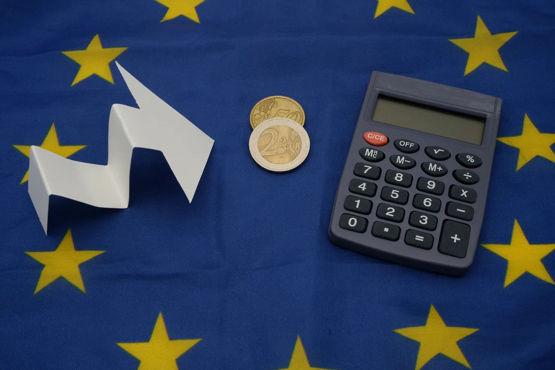 O săgeată care inndică creștere lângă două monede și un calculator, puse pe steagul Uniunii Europene