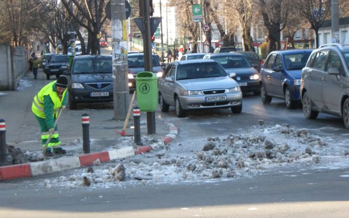 Lucrătorii de la Salubritare iau zăpada de pe trotuar şi o aruncă în stradă