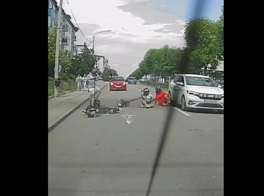 Momentul periculos în care doi copii se prăbușesc cu trotinetele electrice printre mașini. Unul ajunge lângă roțile unui autoturism