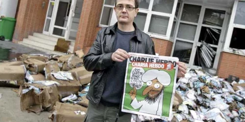 Charb, directorul publicaţiei, prezintă prima pagină a numărului special în faţa redacţiei „Charlie Hebdo”, făcută scrum