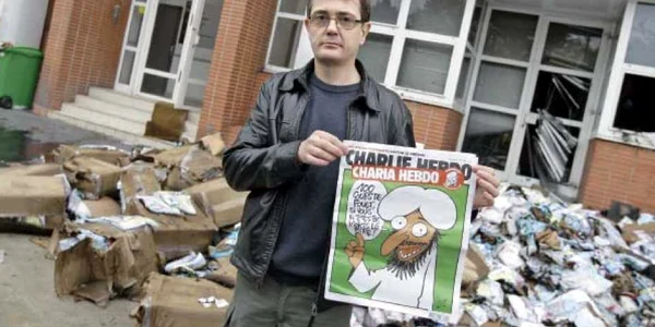 Charb, directorul publicaţiei, prezintă prima pagină a numărului special în faţa redacţiei „Charlie Hebdo”, făcută scrum