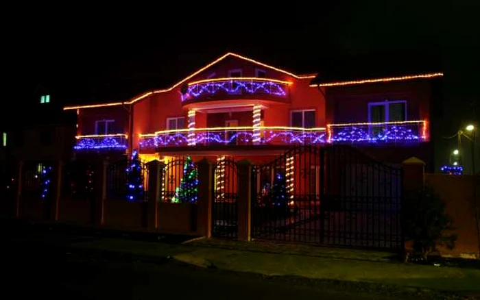 Instalaţia simetrică a casei este în contrast cu luminiţele multicolore care împodobesc brazii