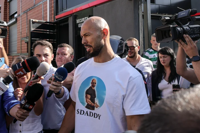 Andrew Tate de vorbă cu presa în timp ce era escortat de jandarmi la DIICOT
