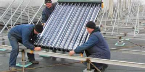 Muncitorii montează panourile solare pe acoperişul clădirilor