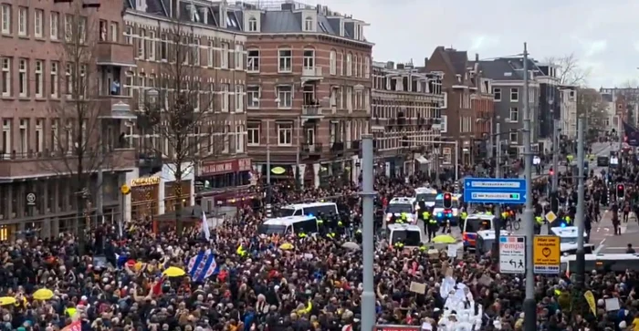 Miii de oameni protestează duminică în Amsterdam, unii dintre ei afişând un banner cu mesajul “mai puţină represiune, mai multă grijă” Foto: Captură video