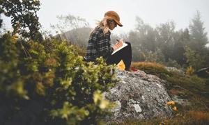 femeie scrie in jurnal in padure pe o piatra munte WA O4UAUfxc(1) jpg