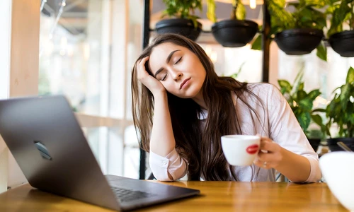 portrait tired young businesswoman sitting table with laptop computer while holding cup coffee sleeping cafe jpg