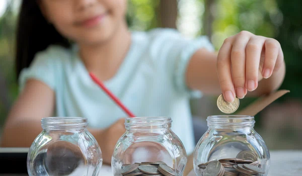 cute asian little girl playing with coins making stacks money kid saving money into piggy bank into glass jar child counting his saved coins children learning about future concept jpg