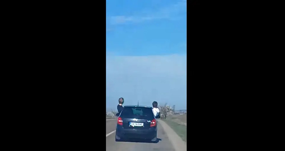 Distracție inconștientă pe o șosea din Suceava. Adolescenți ieșiți pe jumătate dintr-o mașină, filmați în trafic VIDEO
