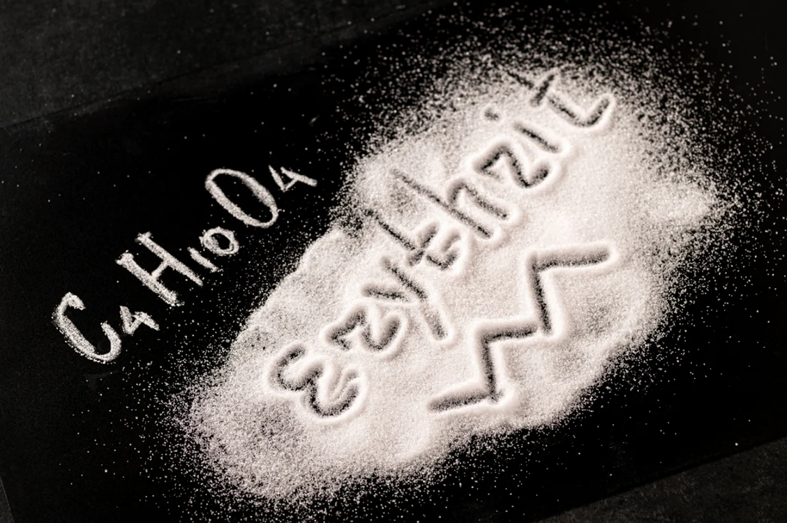 Eritritol pe o masă, plus formula sa chimică