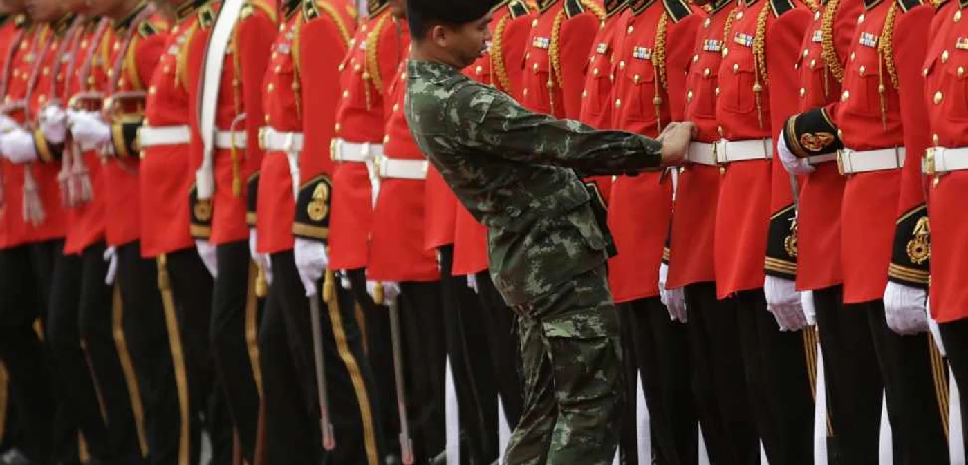Un ofiţer al armatei thailandeze aranjează centura unui membru al gărzii de onoare la pregătirile pentru sosirea primului ministru din Laos Thongloun Sisoulith la Casa Guvernului din Bangkok Thailanda Thongloun este într-o vizită de două zile în Thai