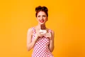 good humoured european girl eating chocolate pinup young woman polka dot dress smiling yellow space jpg