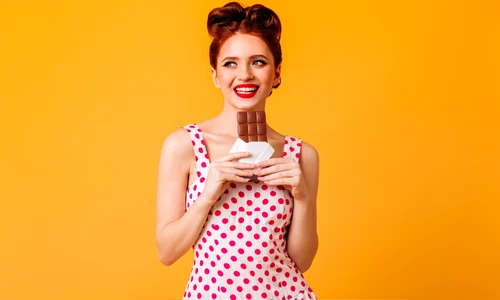 good humoured european girl eating chocolate pinup young woman polka dot dress smiling yellow space jpg