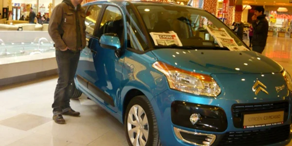 Un tânăr sucevean admiră formele unui automobil expus în showroom