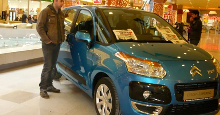 Un tânăr sucevean admiră formele unui automobil expus în showroom