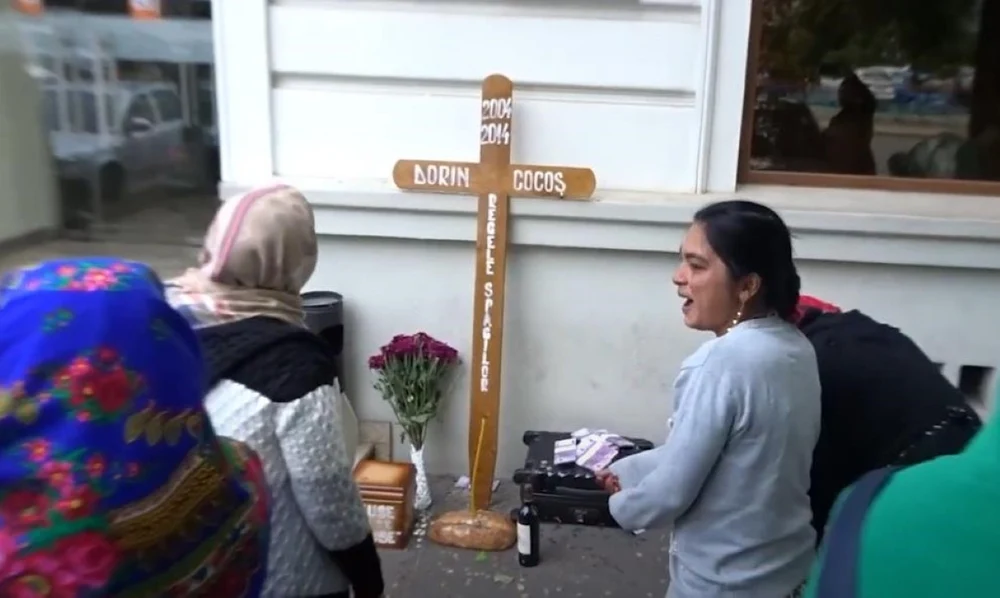 Spectacol grotesc în fața hotelului fostului soț al Elenei Udrea, Dorin Cocoș. Cor de bocitoare, cruce și lumânări. „Regele șpăgilor, fuse și se duse”