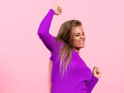 front view young woman posing rejoicing beautiful purple dress pink wall jpg