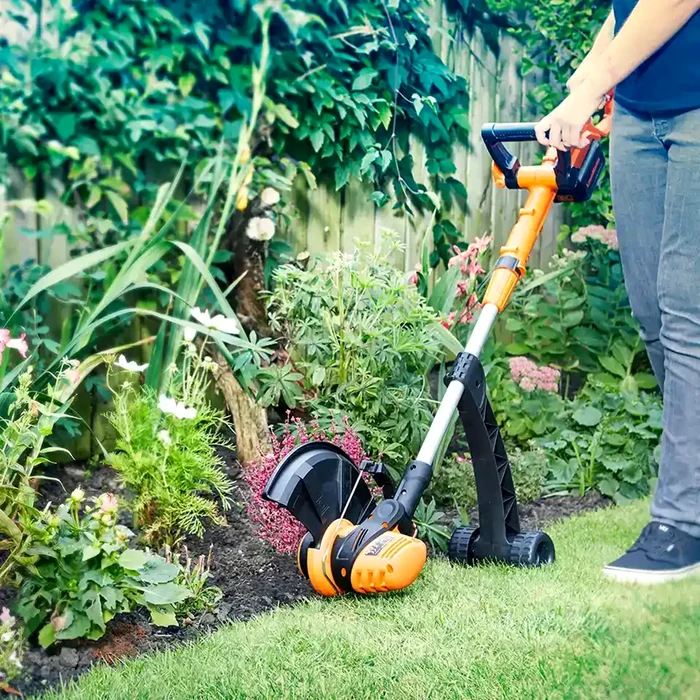 Un trimmer electric / coasă electrică cu fir și cu roți finisând zona dintre flori si gazon ClevaUK