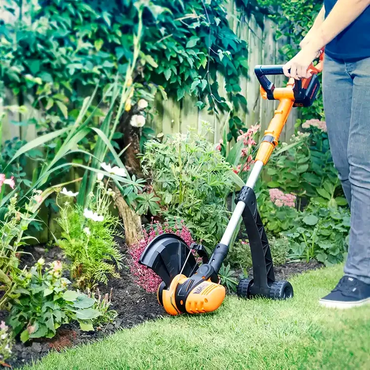 Un trimmer electric / coasă electrică cu fir și cu roți finisând zona dintre flori si gazon ClevaUK