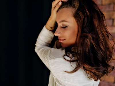 close up portrait attractive pretty woman with tanned skin is touching her hair smiling with closed eyes jpg