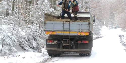 Muncitorii din imagine împrăştiau astăzi dimineaţă material antiderapant pe drumul de acces către pârtiile de pe staţiunea Semenic