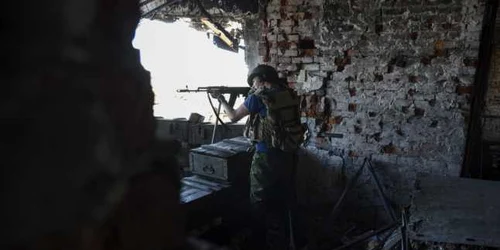 Un rebel pro-rus trage către poziţiile armatei ucrainene de pe aeroportul Doneţk estul Ucrainei FOTO AP
