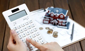 female hand operating calculator front villa house model jpg