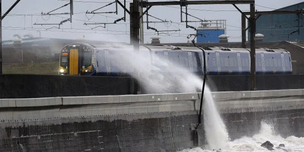 Valuri lovesc un tren care circulă pe linia de nord de la Saltcoats în Ayrshire Scoţia în timp ce furtuna Barbara se abate asupra zonei de coastă britanice FOTO AFP / Andy Buchanan