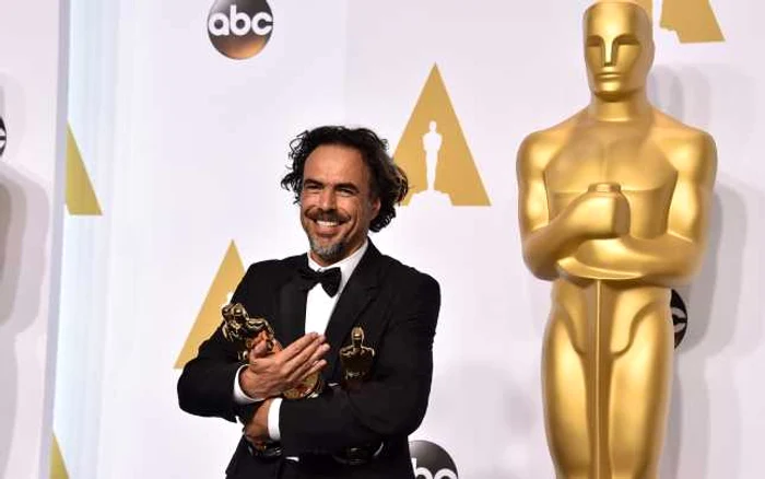 Regizorul mexican Alejandro Iñárritu, ţinând în braţele trofeele Oscar 2015 primite pentru filmul „Birdman” / „Omul Pasăre” FOTO AP