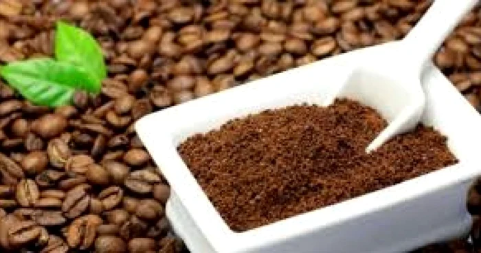 Boabe de cafea lângă un recipient cu cafea măcinată