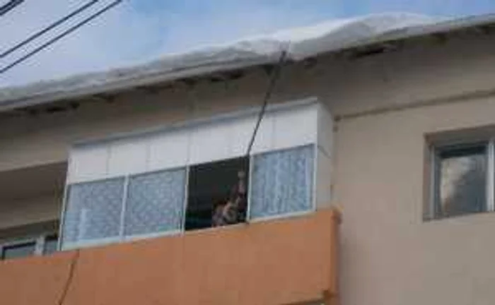 Unii severineni, care locuiesc la etajul patru, curăţă zăpada de pe acoperiş