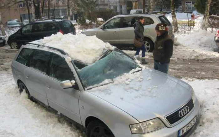 Maşină avariată de zăpada căzută de pe un bloc din Suceava.                            Foto: Sandrinio Neagu