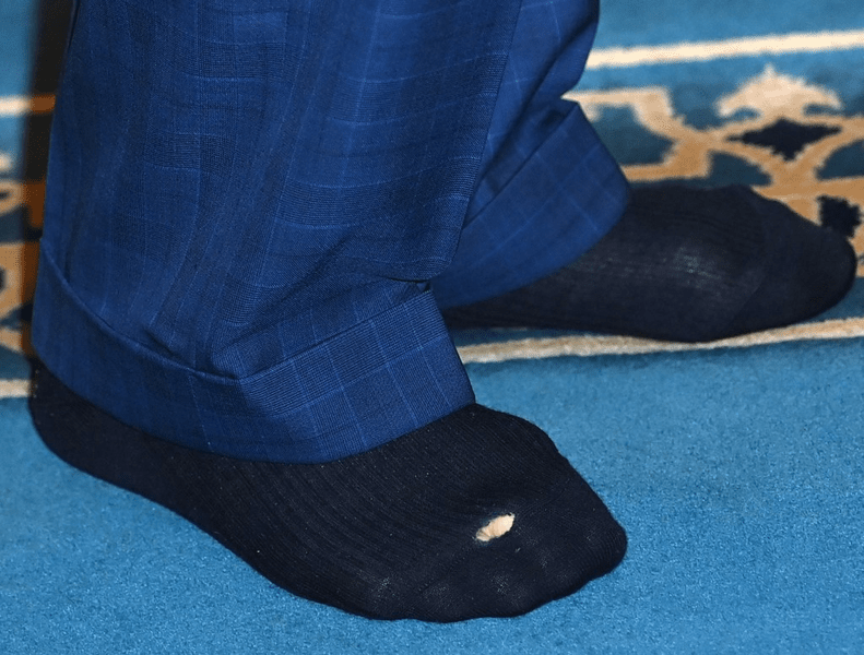  Regele Charles al III-lea, fotografiat cu o gaură în șosetă în timpul unei vizite la o moschee