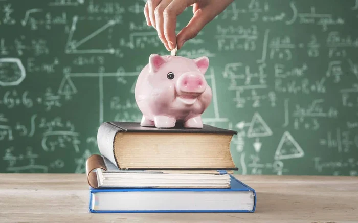 O persoană introduce monede într-o pușculiță în formă de porc