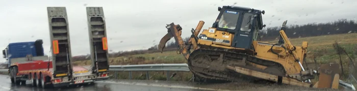 Buldozerul a căzut de pe autotrailer direct într-un șanț