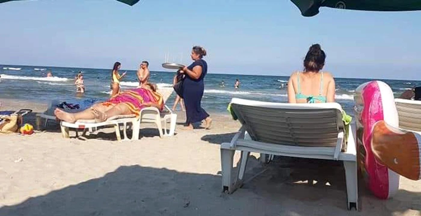 Femeia umblă nestingherită pe plajă cu tava plină cu mere glazurate