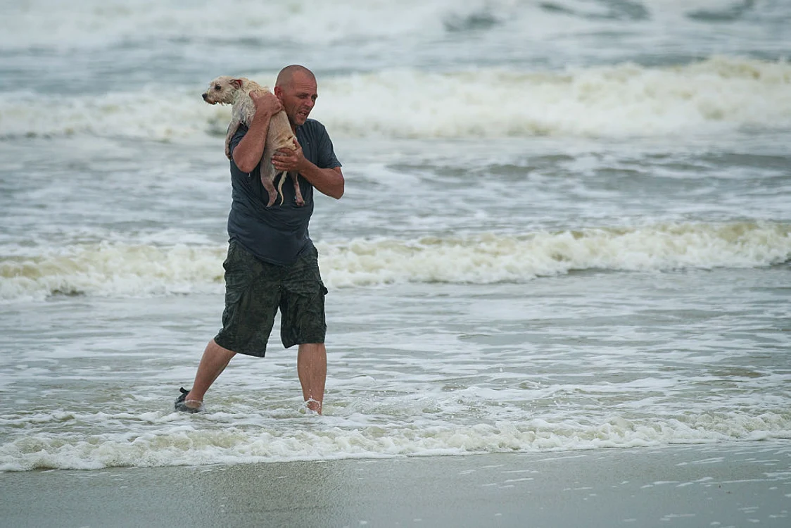 Un bărbat îşi plimbă câinele pe o plajă din Florida