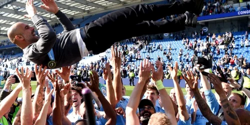 Jucătorii echipei Manchester City îl aruncă în sus pe antrenorul Josep Guardiola în timp ce sărbătoresc câştigarea titlului din Premier League în urma meciului contra celor de la Brighton & Hove Albion pe stadionul American Express Community în Brigh