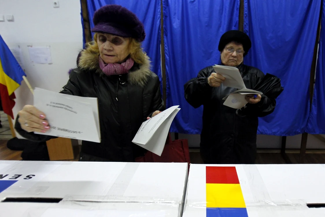 Două doamne cu buletine de vot în mână pregătite să le introducă în urne