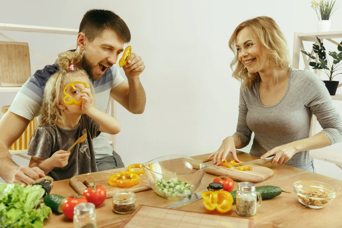Familie cu copil în bucătărie pregătind masa